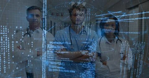 Standing docs checking data in hospital corridor, wearing blue scrubs labcoat Stock Photos