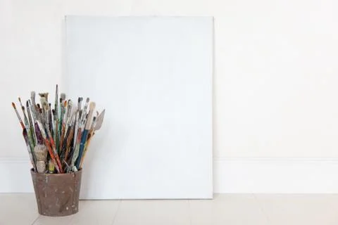 Standing framed canvas with stack of oil paintbrushes and painting knife in Stock Photos