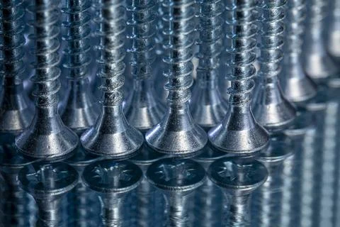 Standing galvanized self-tapping screws on a mirror surface Stock Photos