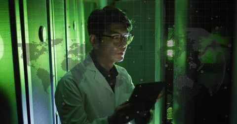 Standing Korean tech in lab coat and glasses, holding tablet inside server room Stock Photos