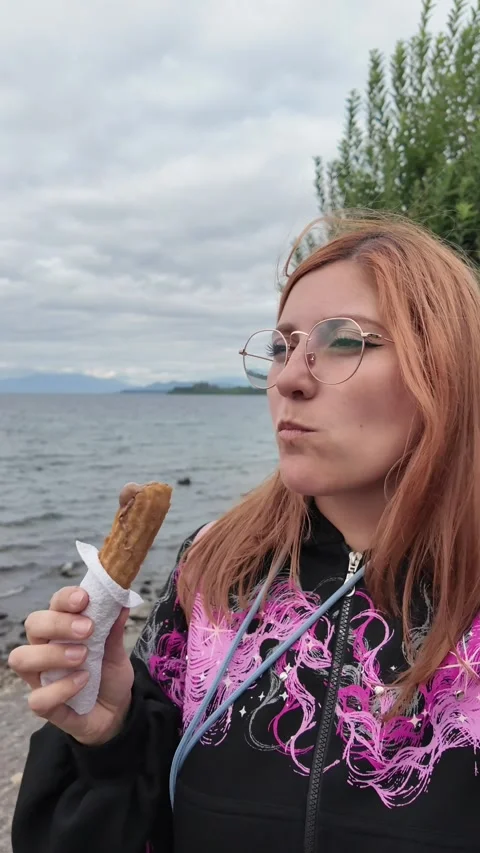 Standing by a Lake Holding a Snack on a Cloudy Day Stock Footage 313190284