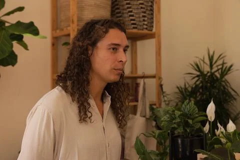 Standing, looking right among plants at home, African American nonbinary person Stock Photos