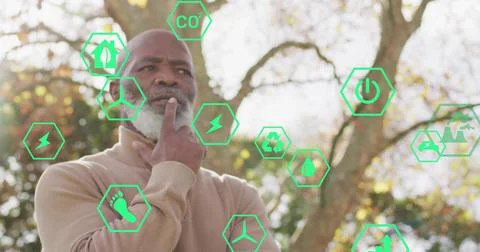 Standing man with gray beard holding chin in autumn park, with green ecology and Stock Photos