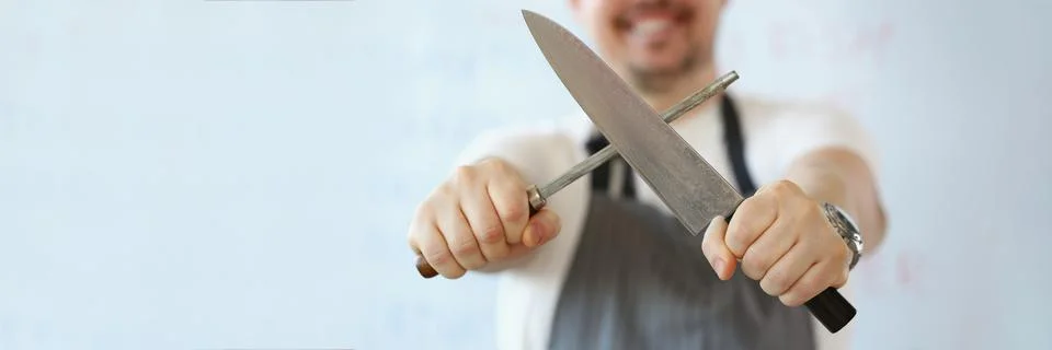 Standing man holding in hand sharp kitchenware for cooking, knife sharpening Stock Photos