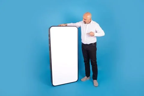 Standing man pointing big empty screen of huge smartphone for mock up. Stock Photos