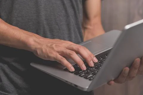 A standing man using a laptop computer Stock Photos