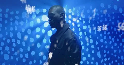 Standing man wearing dark jacket in dark studio, with blue bokeh lights and Stock Photos