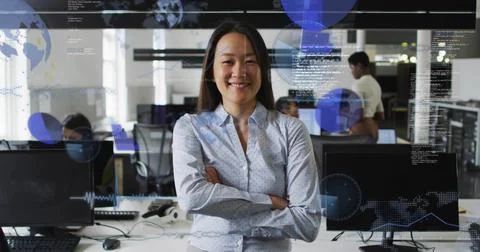 Standing manager wearing patterned top, crossing arms and smiling in open office 写真素材