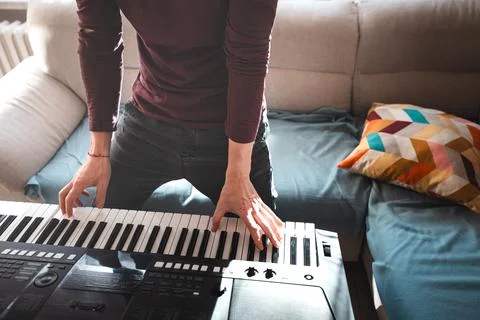Standing musician playing a digital keyboard in a brightly lit living room, s Foto stock