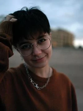 Standing non-binary woman looking at the camera with one arm on her head Stock Photos