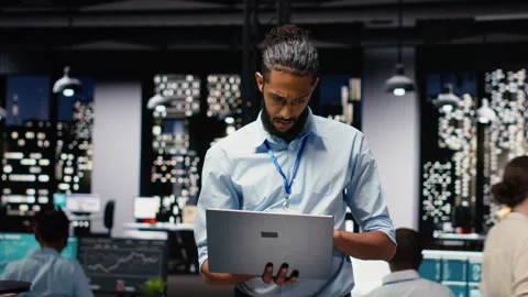 Standing in office, arab manager holds laptop, evaluating performance data Stock Footage 334042431
