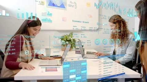 Standing peer joining talk, seated coworkers reviewing charts and using data for Stock Footage 333369015