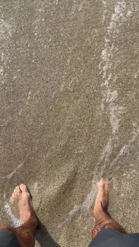 Standing on a sandy beach in bare feet and waiting for the waves Stock Footage 322073226