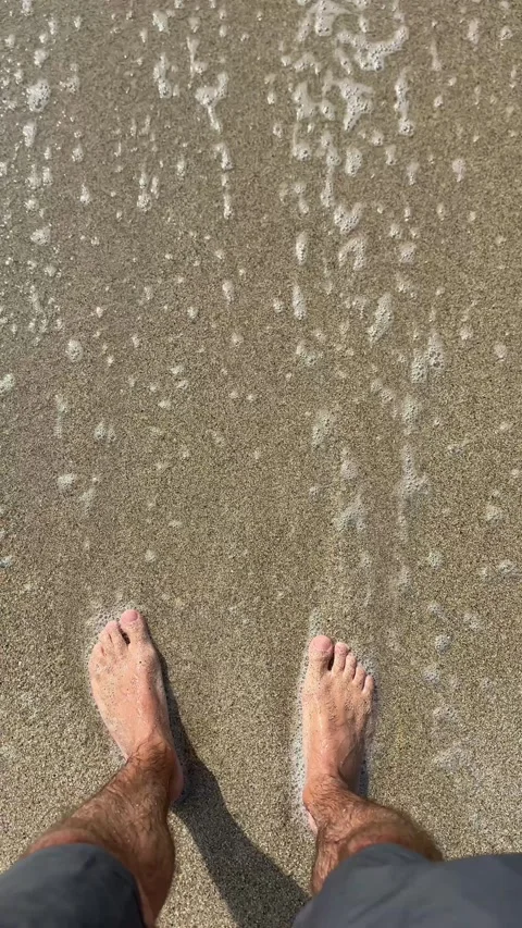 Standing on a sandy beach in bare feet and waiting for the waves Stock Footage 322073231