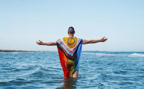 Standing in the sea wrapped in a progress pride flag Stock Photos