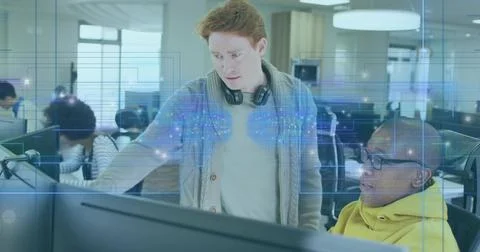 Standing software engineer in cardigan and headphones next to developer in Stock Photos