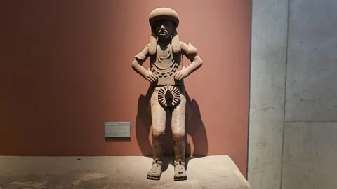 Standing Stone Figure With Hands on Hips Against Red Wall, Mexico 8K Stock Footage 340368883