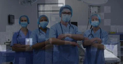Standing surgical team facing camera in operating room, wearing scrubs masks Foto stock