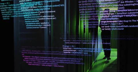 Standing tech in dark jacket inspecting data center racks with green LEDs and Foto stock