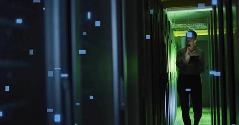 Standing tech in light shirt, pants, inspecting server racks in data center with Foto stock