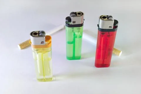 Standing three multicolored disposable flint gas lighters and two filter ciga Stock Photos