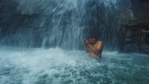 Standing under a waterfall with a local guide in Cambodia, Kampot Stock Footage 100785844