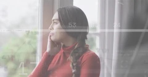 Standing woman with braid in red turtleneck gazing out window at blurred Stock Photos