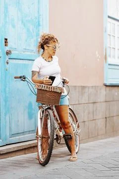 Standing woman in outdoor leisure activity ride a bike outside the blue doo.. Stock Photos