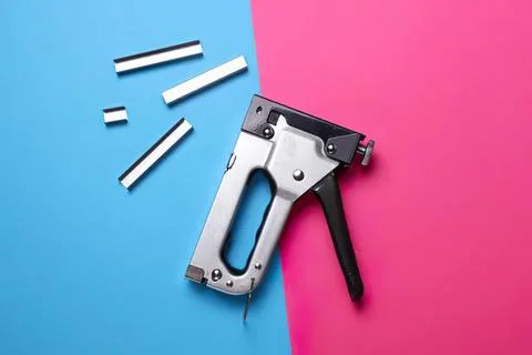 Stapler with white and black staples on pink and blue background Stock Photos