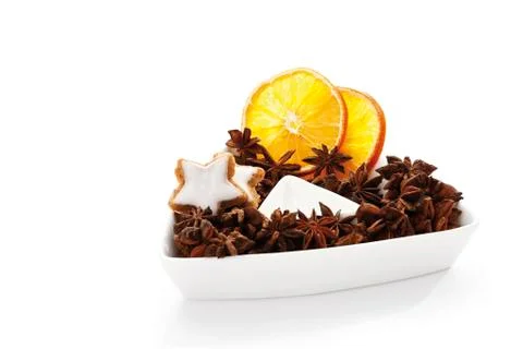 Star anise, cinnammon star-shaped biscuits and dried orange slices in white p Stock Photos