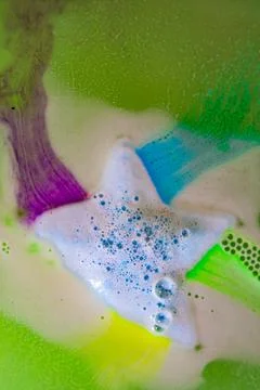 The star-shaped bath bomb dissolves with multicolored paints in water Stock Photos