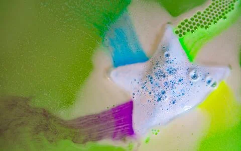The star-shaped bath bomb dissolves with multicolored paints in water Stock Photos