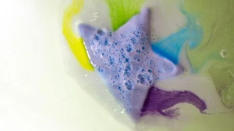 The star-shaped bath bomb dissolves with multicolored paints in water Stock Photos