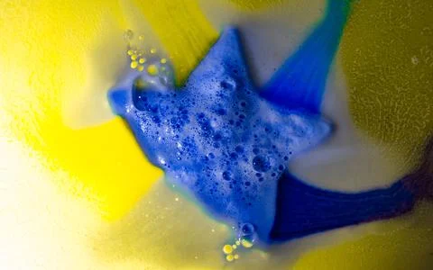 The star-shaped bath bomb dissolves with multicolored paints in water Stock Photos