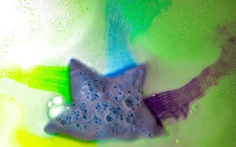 The star-shaped bath bomb dissolves with multicolored paints in water Stock Photos