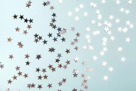 Star shaped silver sequins over blue background. Stock Photos