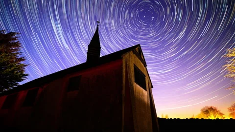Star trails time lapse of dark night sky over light painted chapel 库存影片 152742065