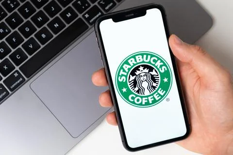 Starbucks coffee the application is open in the smartphone. The man is holding a Stock Photos