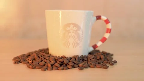 A Starbucks coffee mug with roasted coffee beans on table Stock Footage 145704161