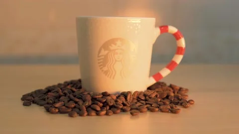A Starbucks coffee mug with roasted coffee beans on table Video stock 145704181