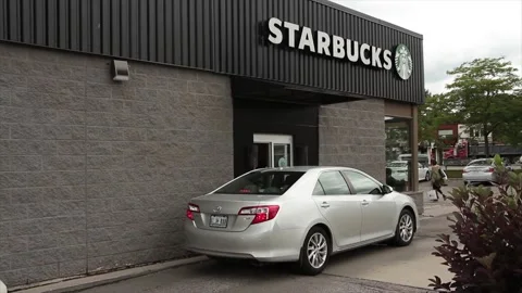 Starbucks drive thru with vehicle pulling away and another pulling up to window Stock Footage 247142605