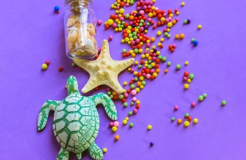 Starfish, turtle, bottle seashells. Multi-colored balls on a purple background Stock Photos