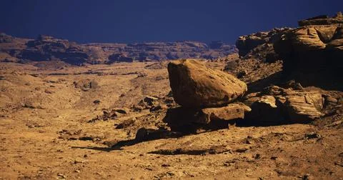 Stark landscape with large rocks under a clear blue sky during daylight Stock Illustration