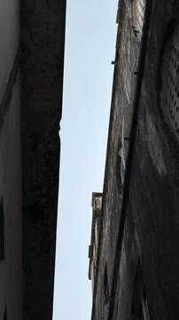 A stark perspective looking up at the sky framed by tall, worn building exter Stock Photos