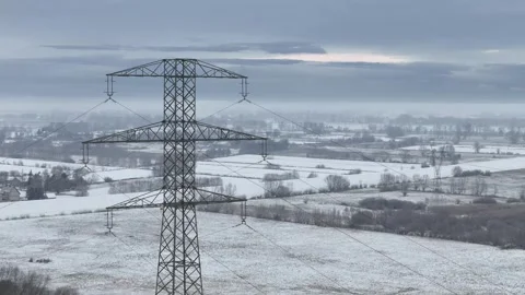 Stark Power Lines Over a Snow-Brushed Landscape Stock Footage 258142454