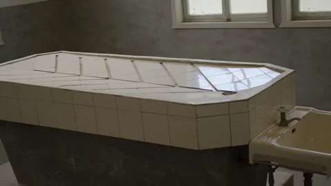 A stark, tiled autopsy table with a raised design, paired with a sink. Vídeo Stock 299049437