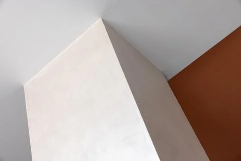 A stark white angular corner meets a burnt orange wall, showcasing bold geo.. Stock Photos