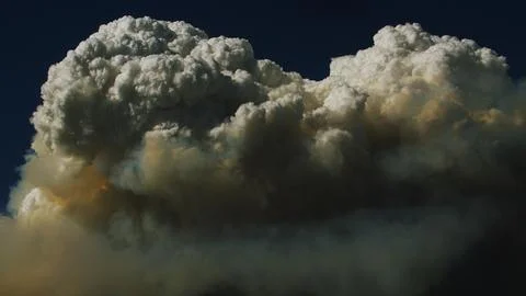 Starkly defined pyrocumulus clouds menace the deceptively calm blue sky. Stock Photos