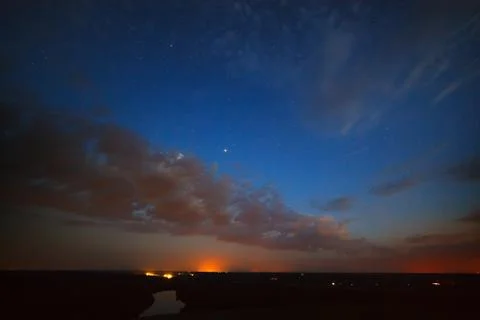 Starry cloudy night sky above the river. Stock Photos