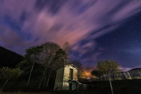 Starry night sky with clouds over a small shed Foto stock
